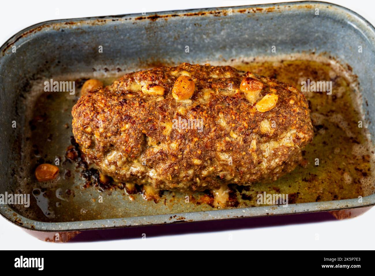Baked whole chopped beef meatloaf with garlic and onion in old rural pan, closeup. Stock Photo