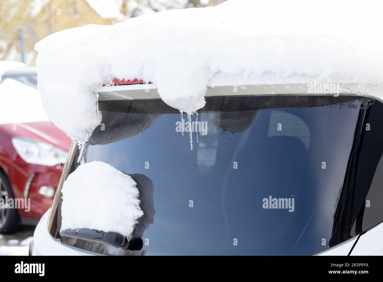 A car covered in snow with hanging icicles, The beginning of winter, snowfall and a drop in temperature Stock Photo