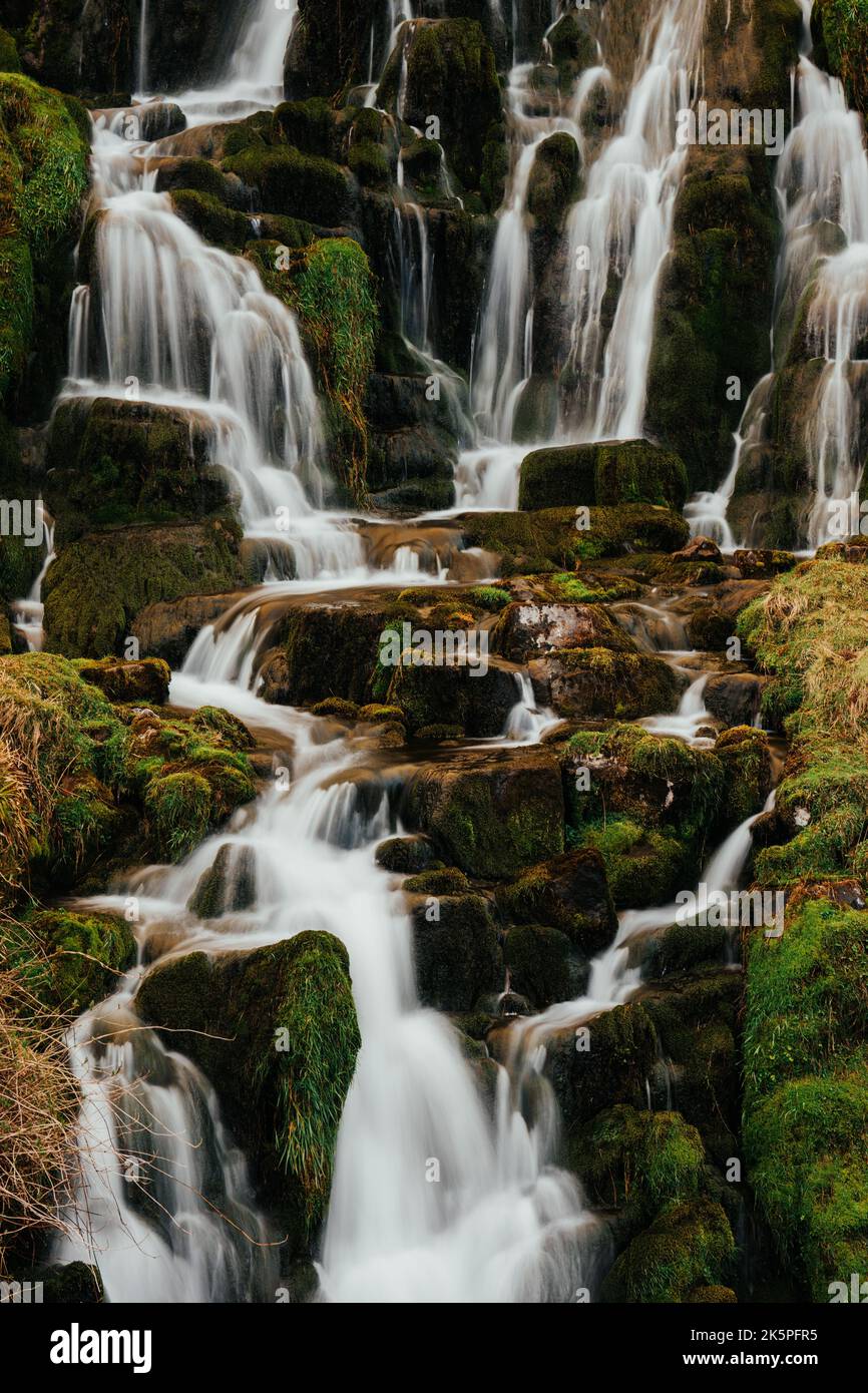 A beautiful waterfall flowing down the rocks covered in moss Stock ...