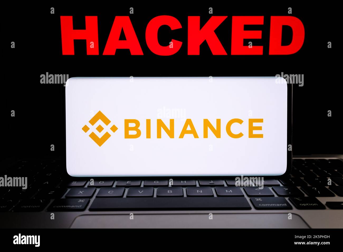 Binance crypto exchange hacked. Binance logo seen on smartphne and red text 'HACKED' seen on laptop. Concept. Stafford, United Kingdom, October 9, 202 Stock Photo