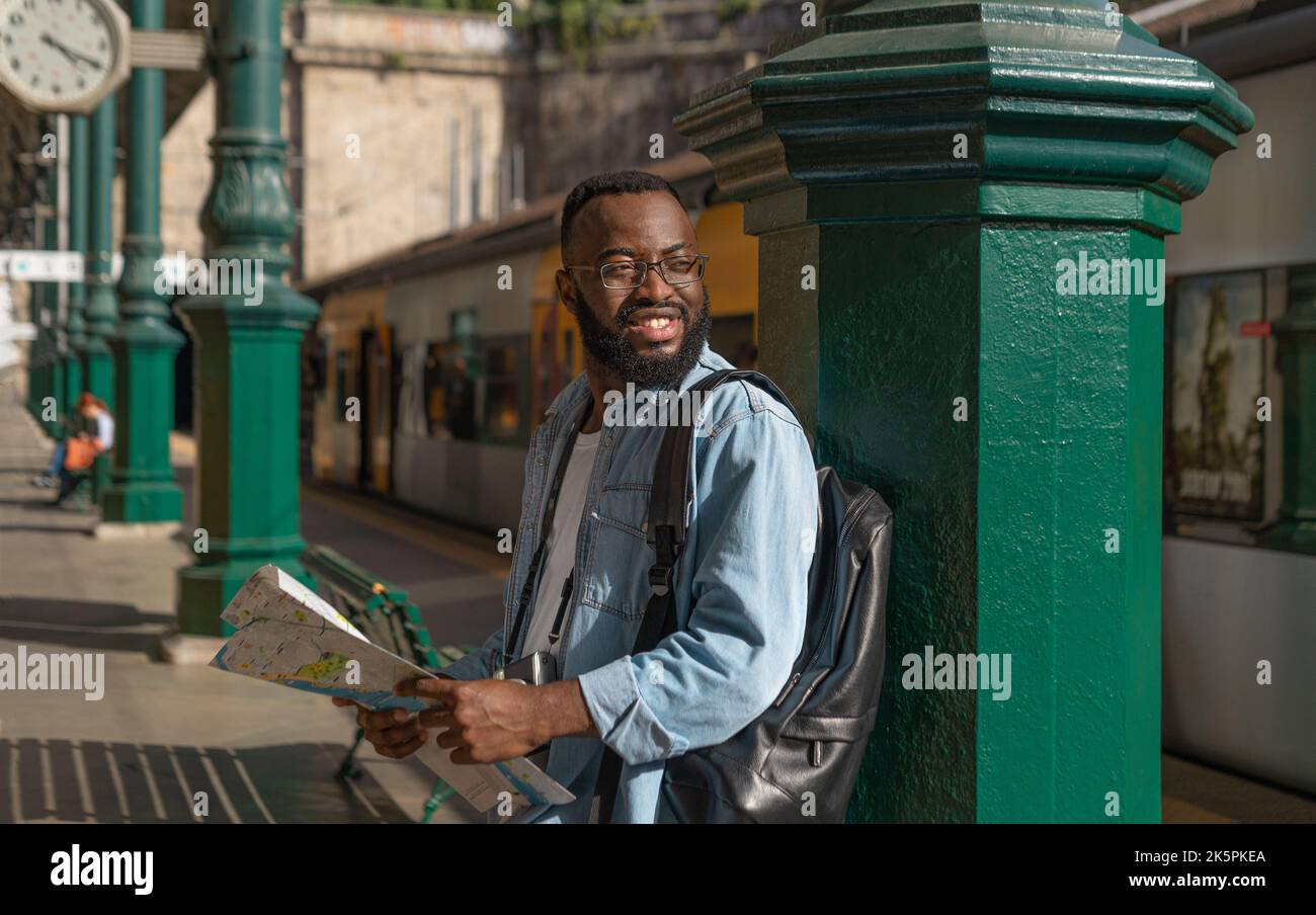 Happy young man with map at terminal train station Stock Photo