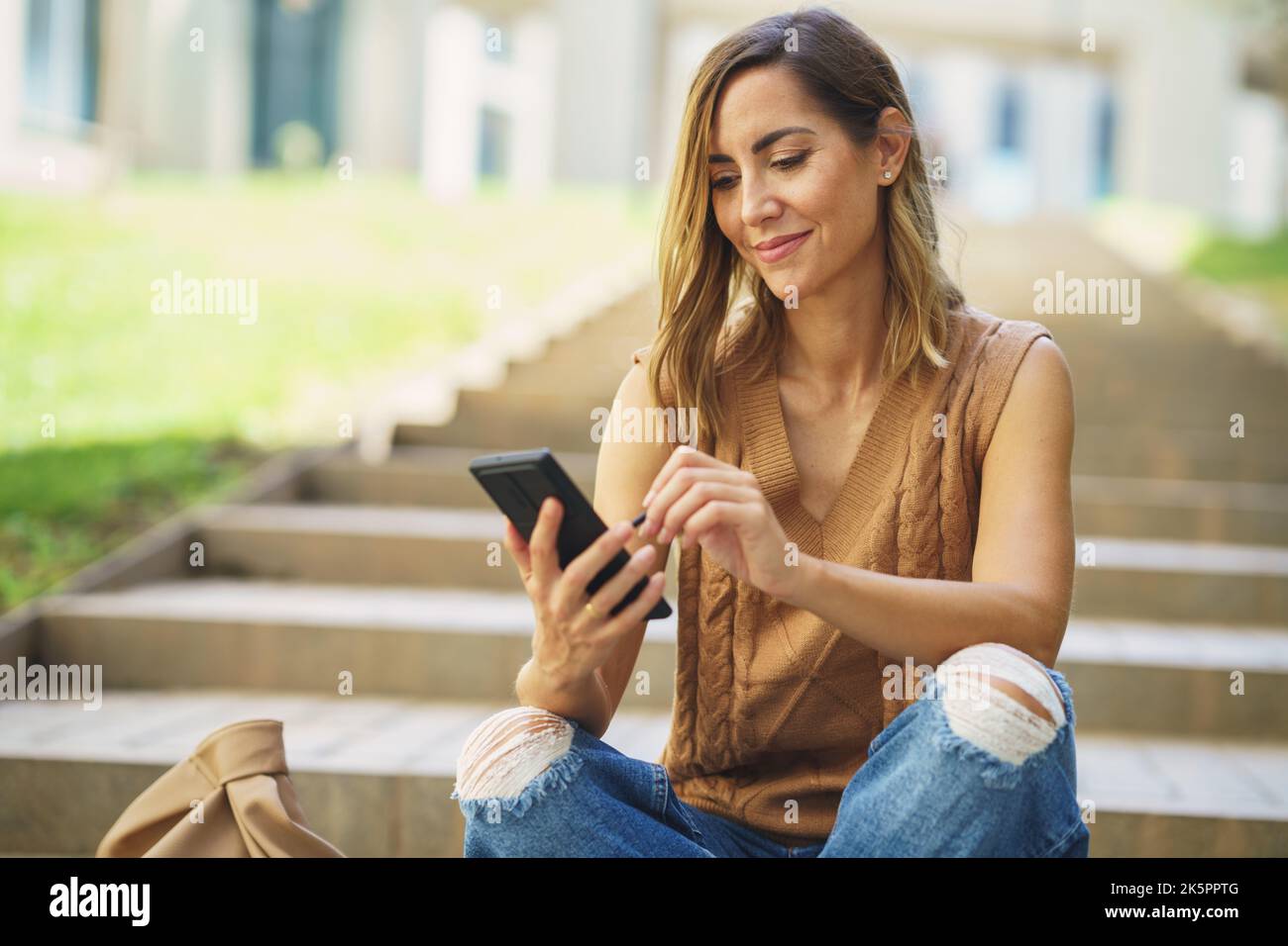 Middle aged using her smartphone with a pen or stylus, outdoor. Stock Photo