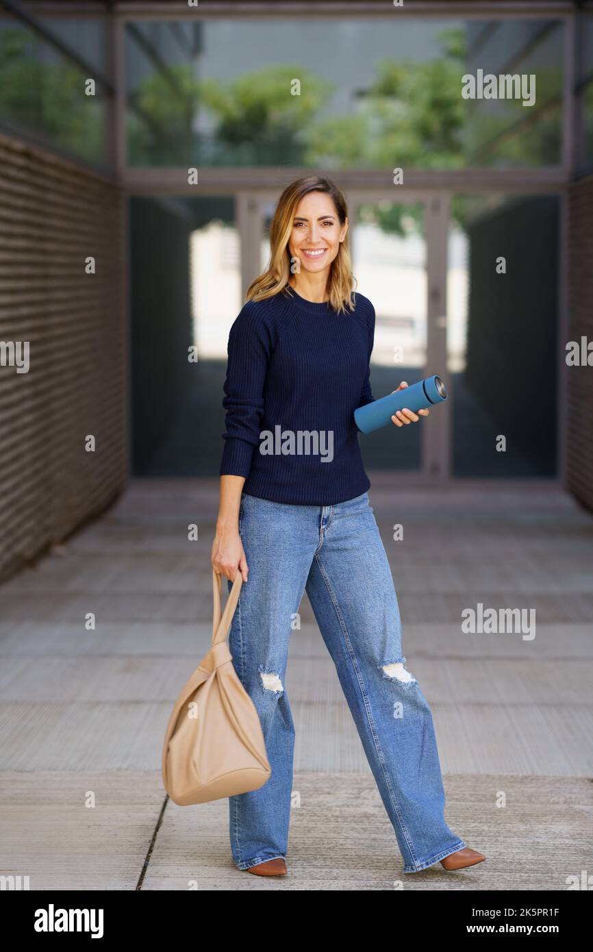 Middle-aged woman carrying a bag and an eco-friendly ecological metal thermos for coffee. Stock Photo