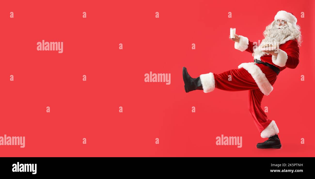 Walking Santa Claus with tasty cookies and glass of milk on red background with space for text Stock Photo