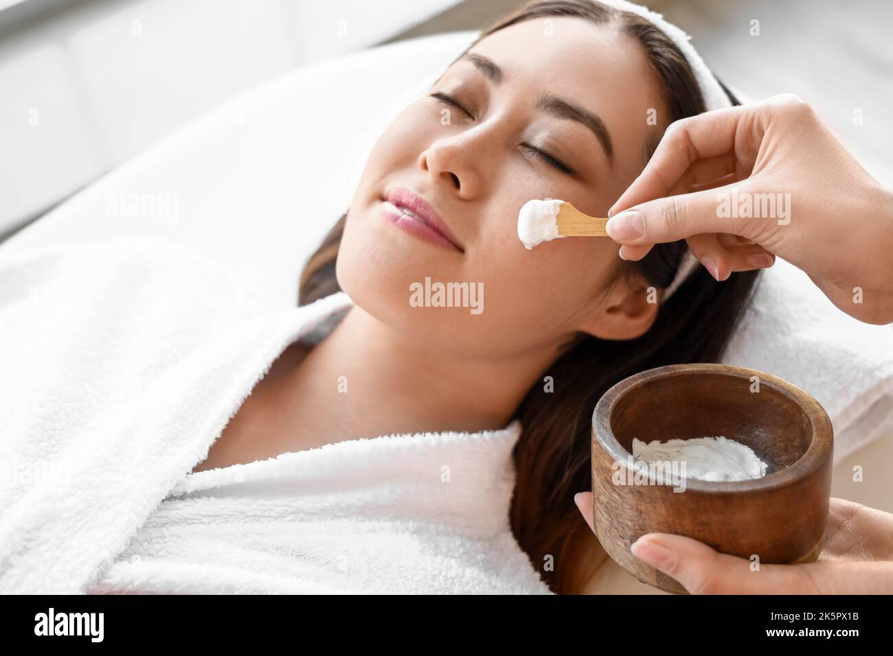 Beautician applying mask on face of young Asian woman in spa salon Stock Photo Alamy