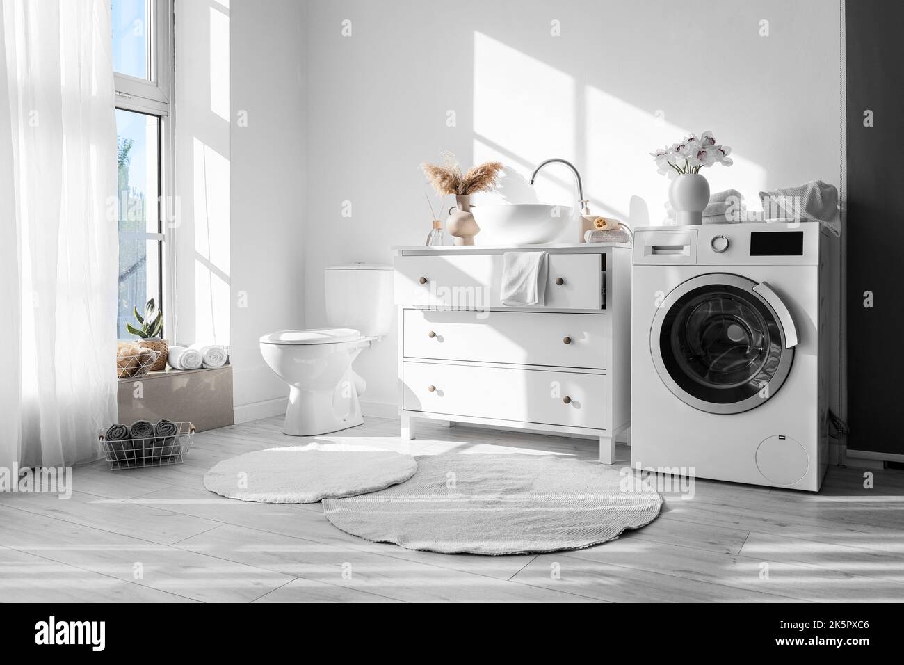 Modern interior of bathroom with washing machine, sink and toilet bowl