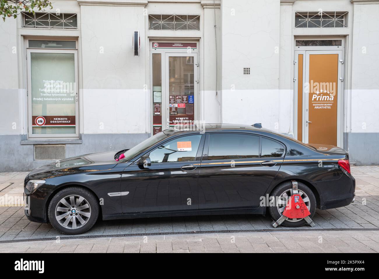 Budapest, Hungary – October 4, 2022. Car with a wheel clamp on a Budapest street. The red lock is placed on a wheel for improper parking to make sure Stock Photo