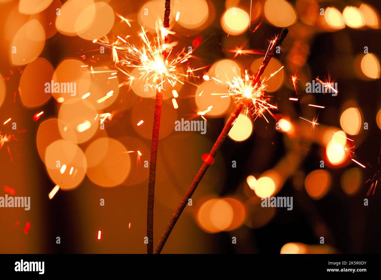 Sparkling bengal fire in the hands on shining bokeh background.Bengal lights on garlands.Christmas shining sparkling blurred background. Stock Photo