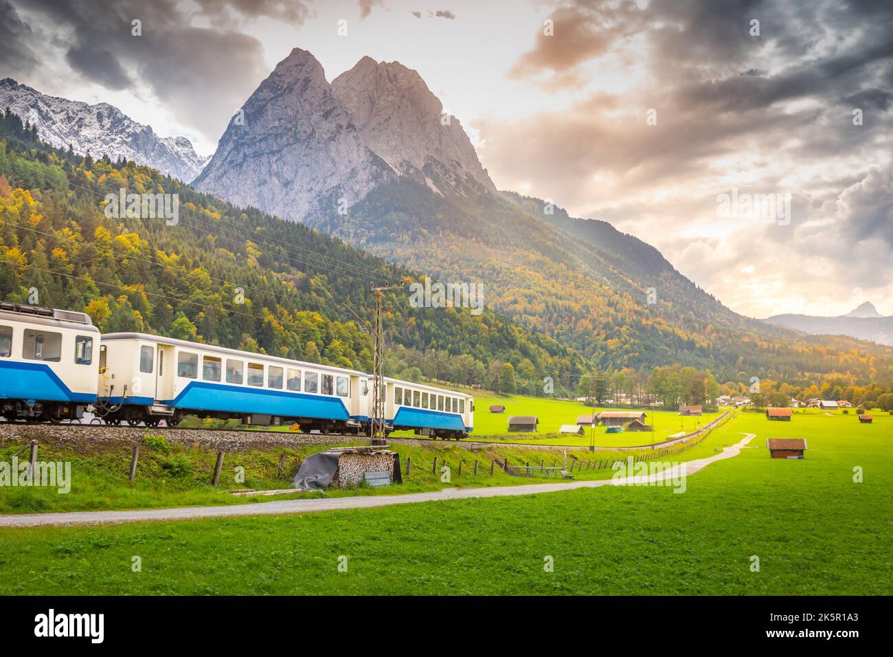 Train in Bavarian alps at autumn and wooden barns at sunset, Garmisch, Germany Stock Photo