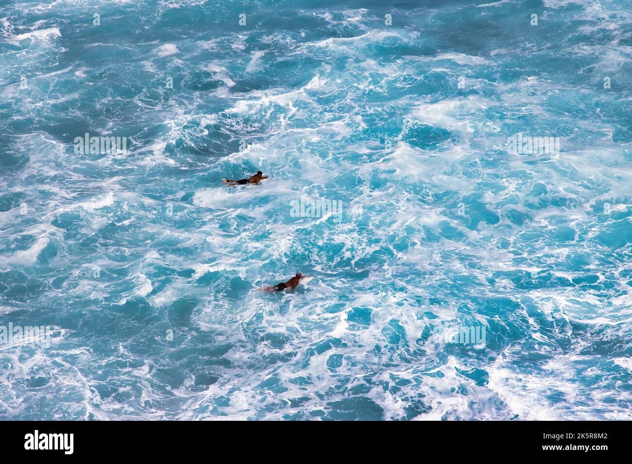 Two unidentifiable surfers coming back to shore after surfing. Stock Photo