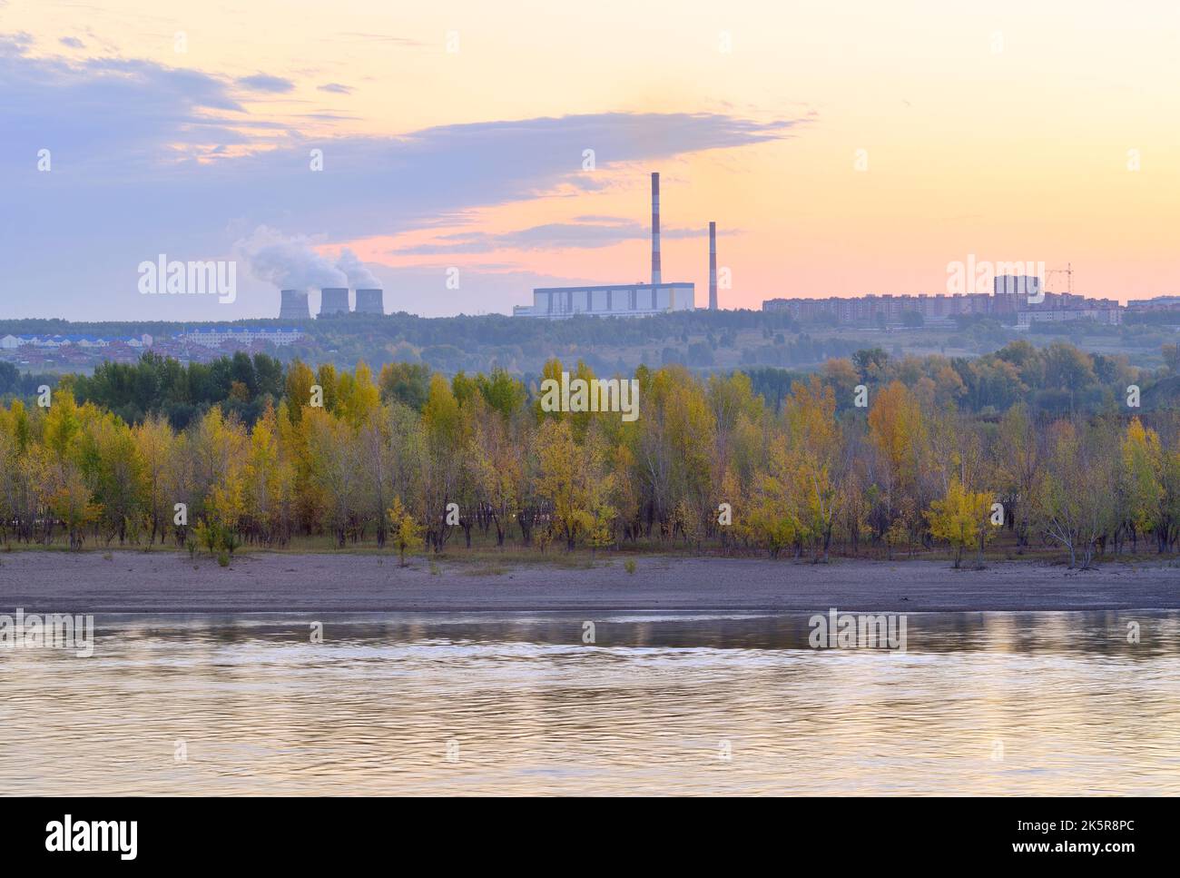 The shore of the Ob at dawn. Autumn forest by the river, CHP-5 pipes on the horizon. Novosibirsk, Siberia, Russia, 2022 Stock Photo
