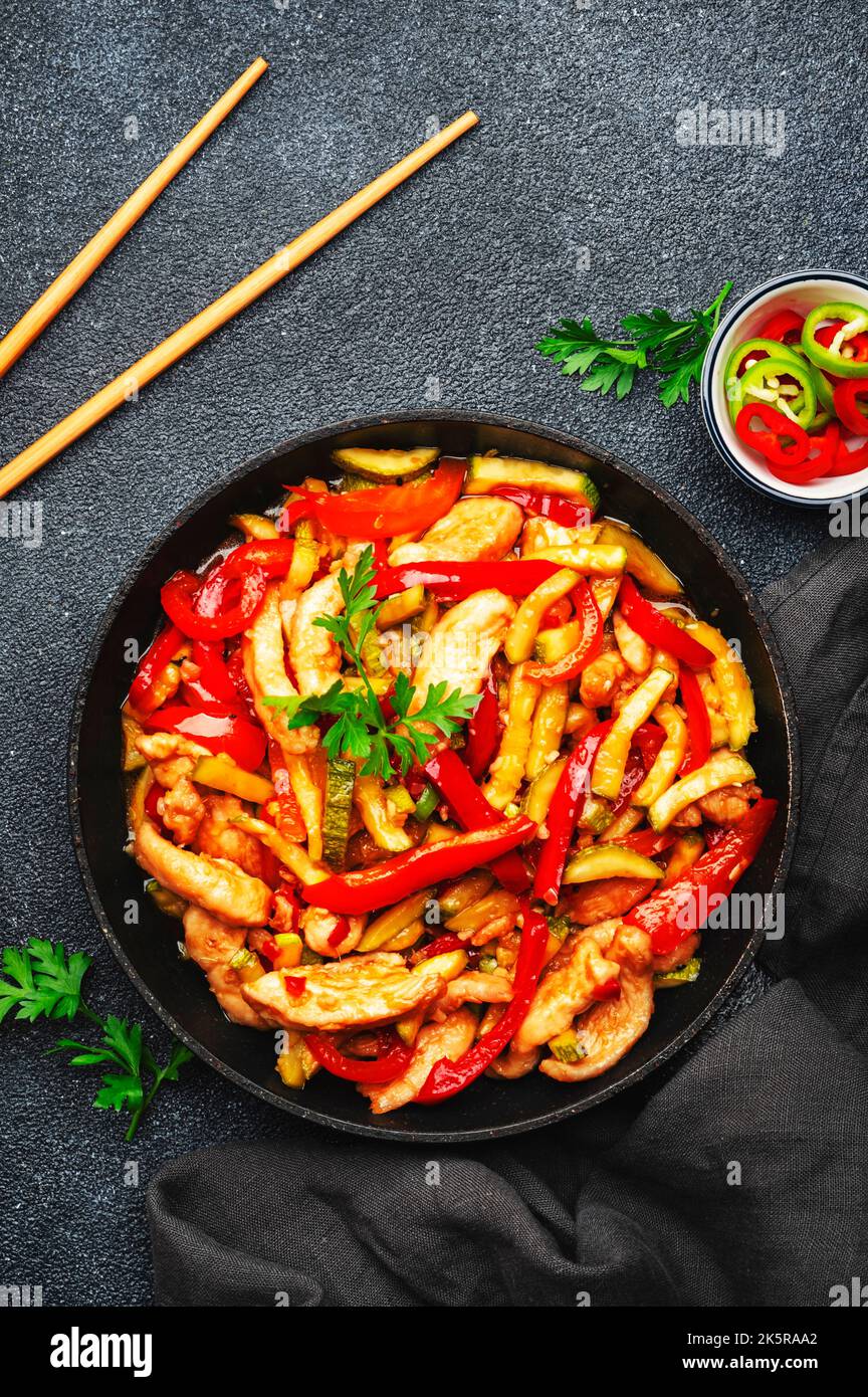 Asian cuisine, stir fry with chicken, red paprika pepper and zucchini