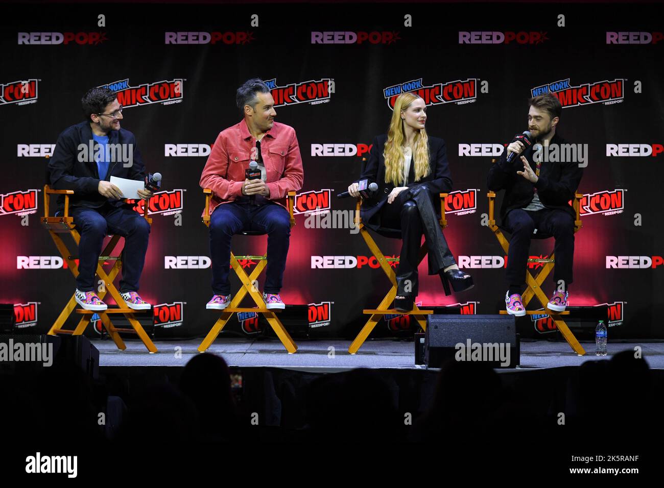 Josh Horowitz, Eric Appel, Evan Rachel Wood and Daniel Radcliffe speak onstage at Let's Get WEIRD panel during New York Comic Con 2022 on October 09, Stock Photo