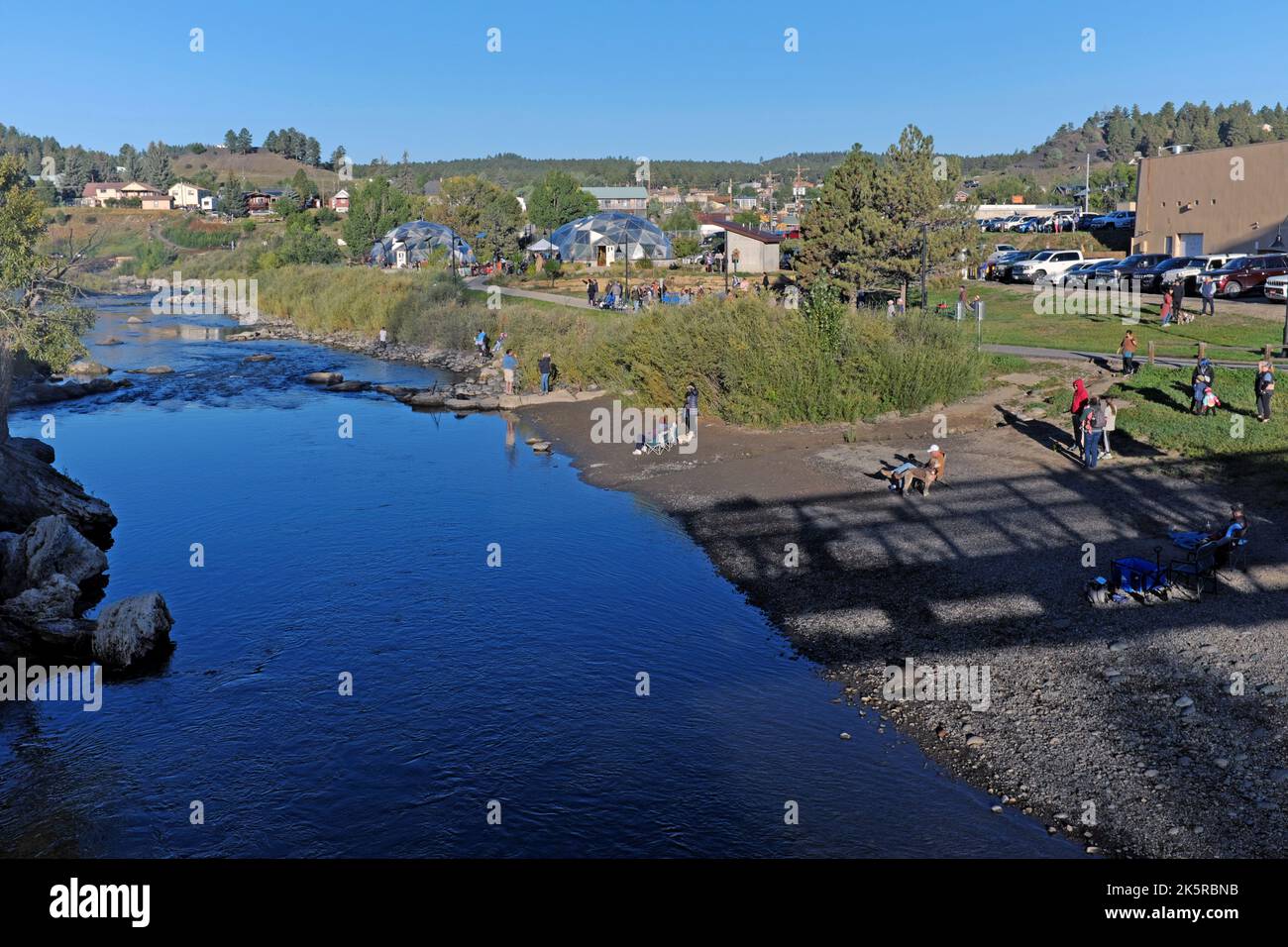 People gather on the bank of the San Juan River in downtown Pagosa Springs, Colorado before the start of the 2022 Colorfest Hot Air Balloon Rally. Stock Photo