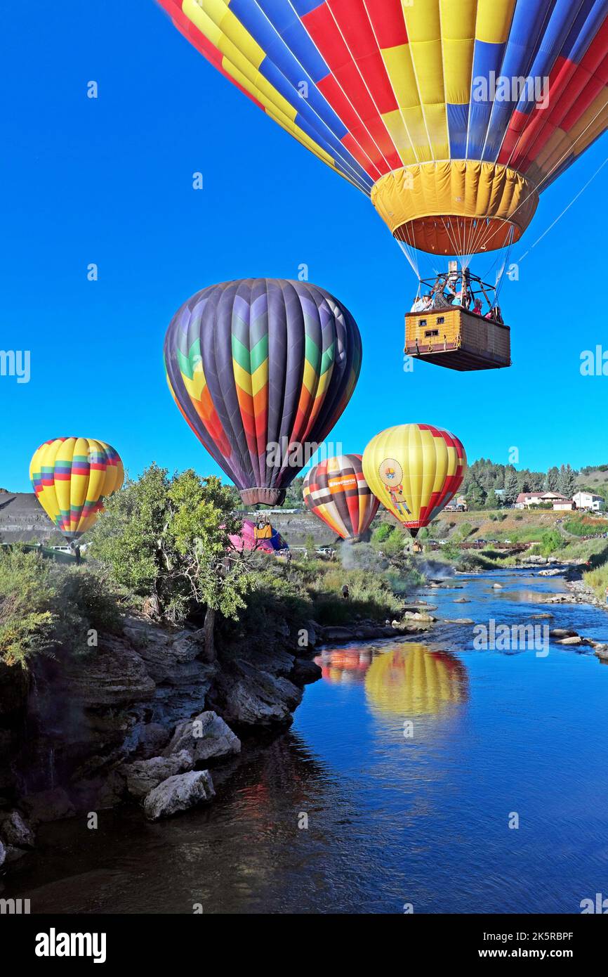 Colorful hot air balloons float over the San Juan River during the 2022 Colorfest Hot Air Balloon Rally in Pagosa Springs, Colorado, USA. Stock Photo