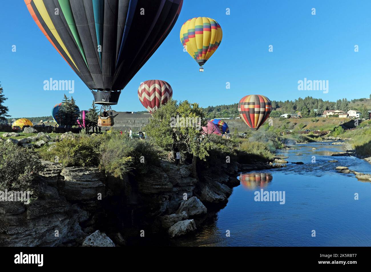 The annual Colorfest Balloon Rally on September 17, 2022, in Pagosa Springs fills the skies with hot air balloons reflected in the San Juan River. Stock Photo