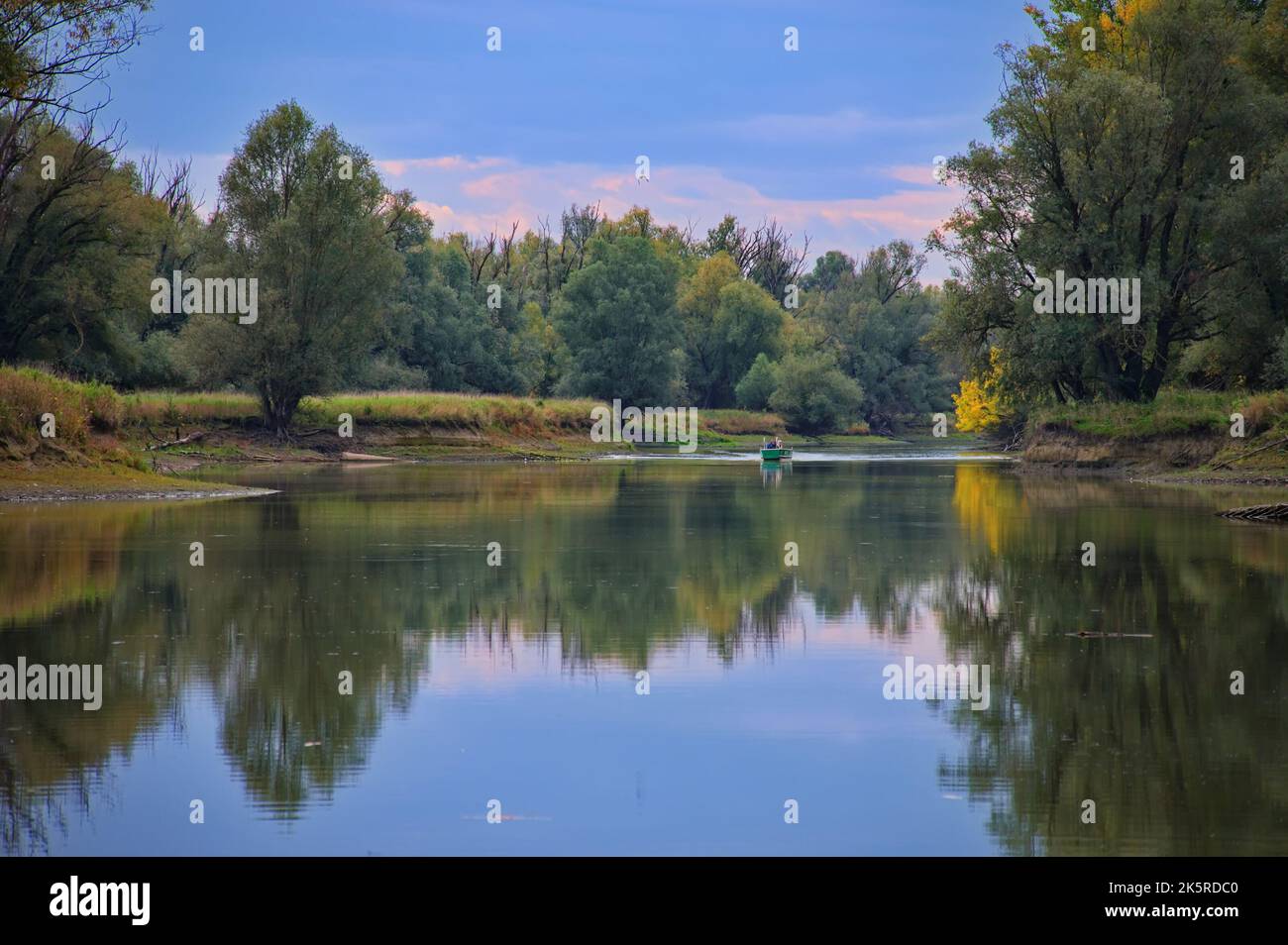 Scenic view of the calm river with autumn trees reflecting in it Stock Photo