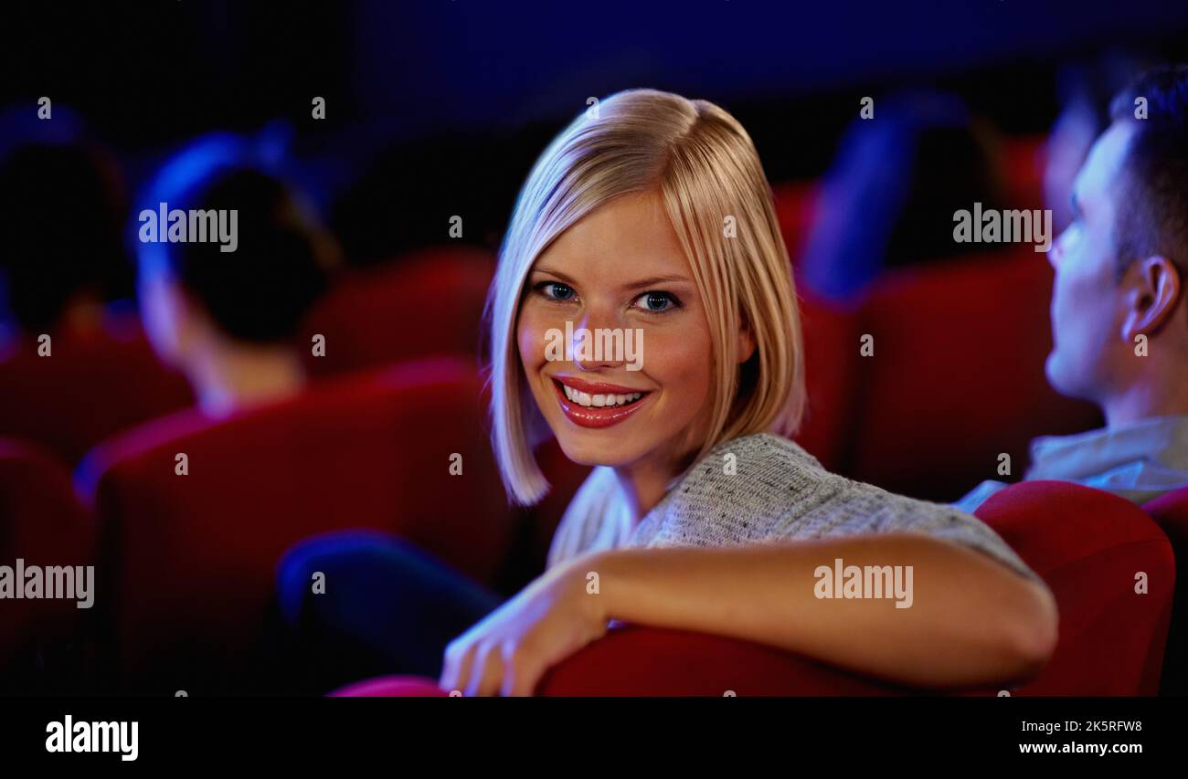 How I like to spend my friday nights. Portrait of a pretty young woman leaning back on a chair a movie cinema. Stock Photo