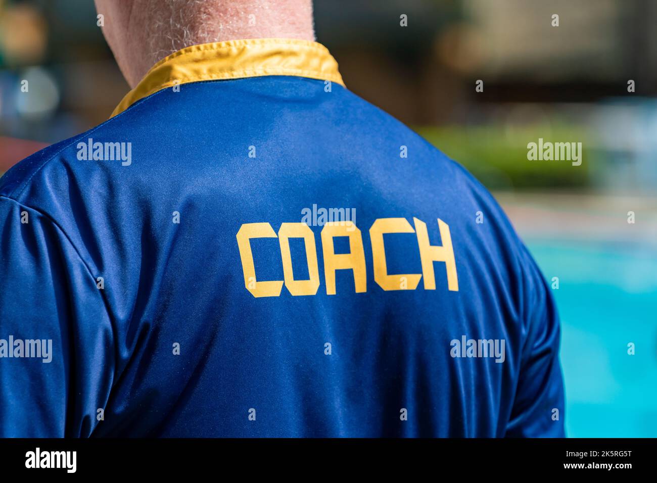 Back view of swimming coach, wearing COACH shirt, working at an outdoor