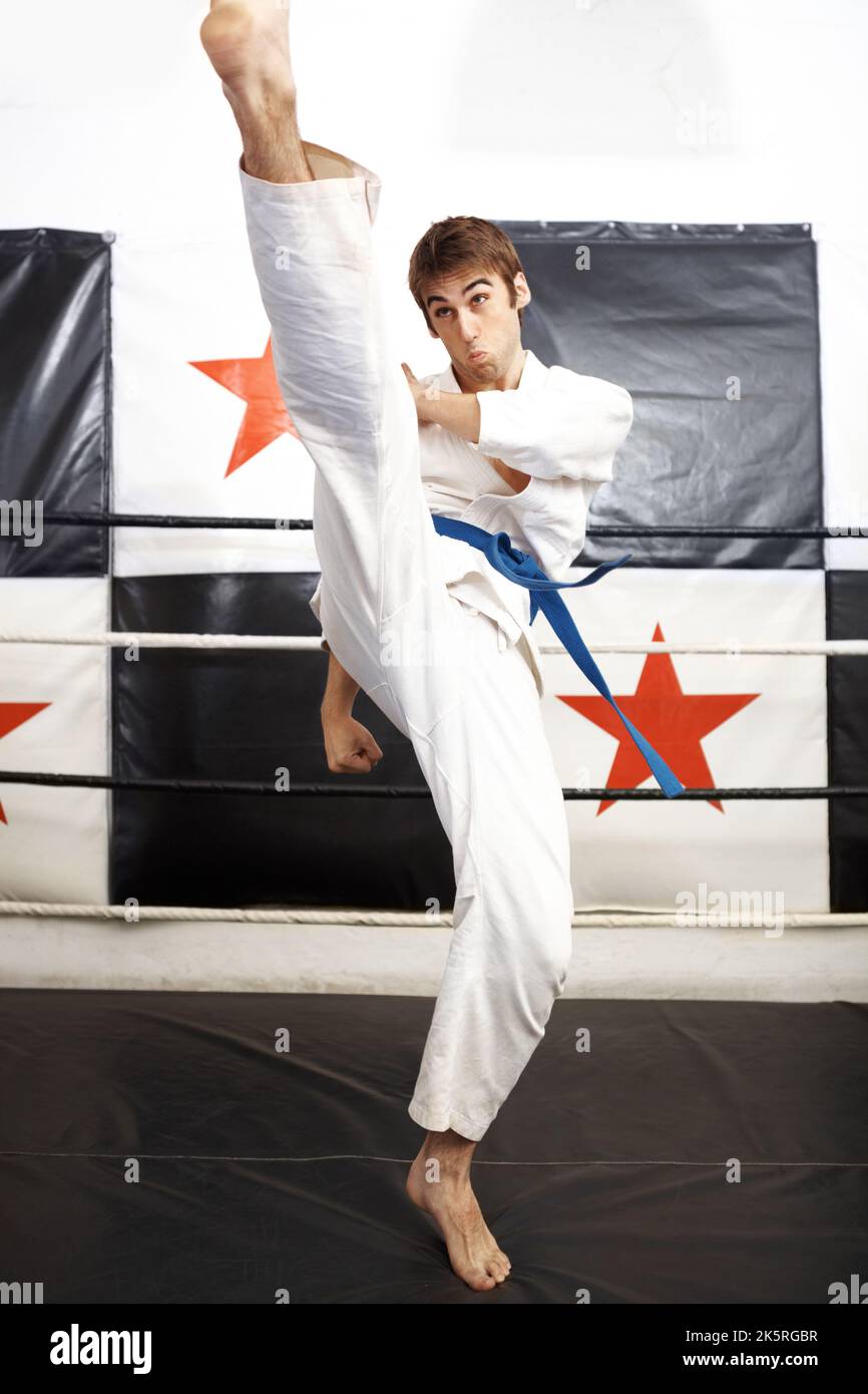 Roundhouse kick. Full length shot of a young martial artist practicing karate in the ring. Stock Photo