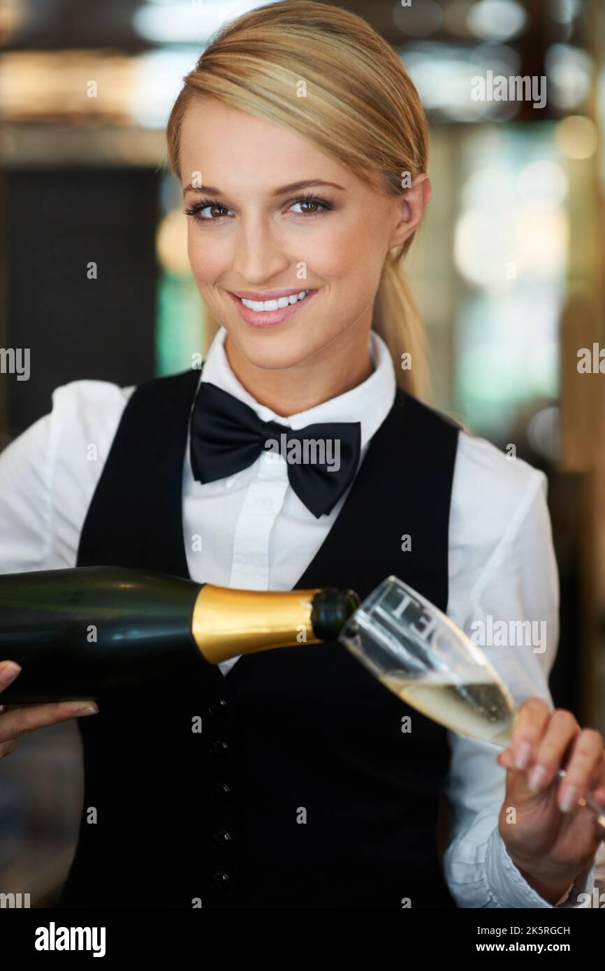 Lets toast to you. Attractive waitress pouring champagne into a
