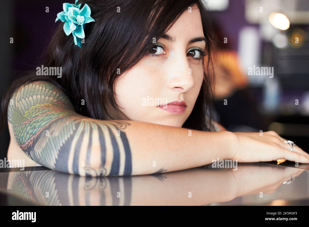 Expressing her identity through art. A young tattoo artist showing off her half-sleeve tattoo while resting her head on her arm. Stock Photo
