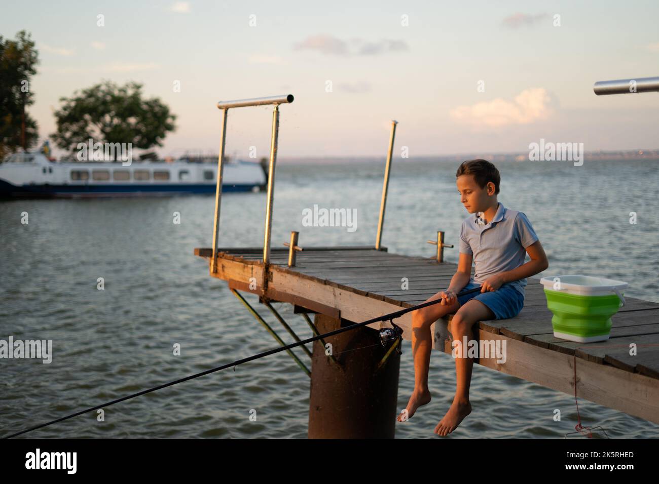 Child fishing on the lake. Kid fisher boy with spinner rod at river