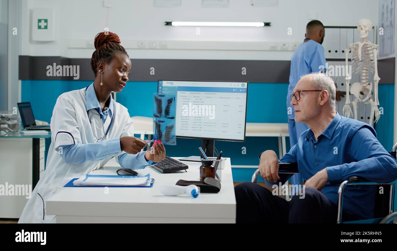 Woman medic showing x ray scan results to patient in wheelchair