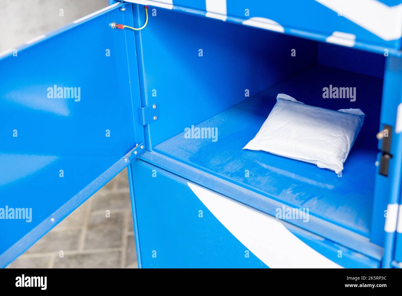 Parcel in locker of automated postal box. Package delivered to the client in self-service post terminal. Open door in deposit locker at contactless po Stock Photo