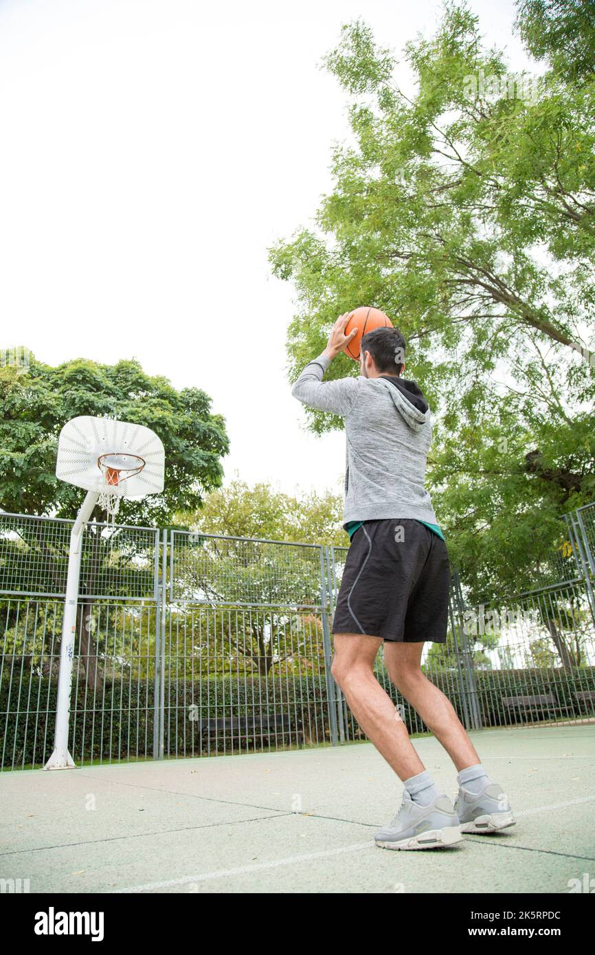 Vertical photo with low angle view of a man throwing a ball on an