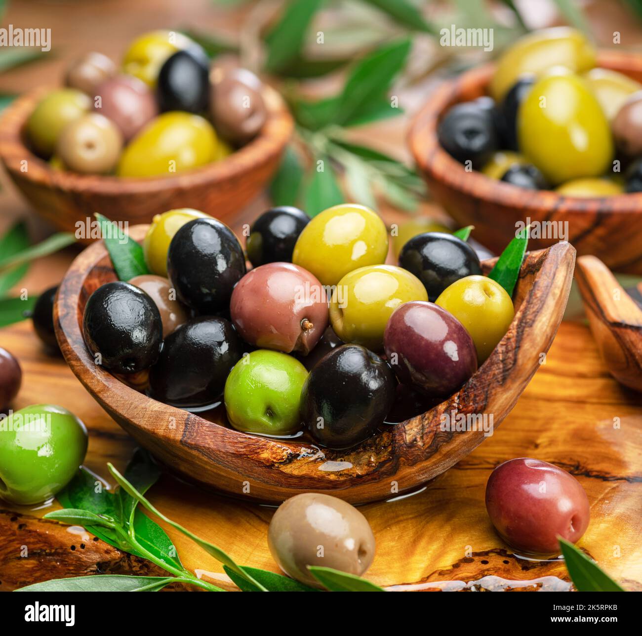 Kalamata, green and black olives in the wooden plates. Food background
