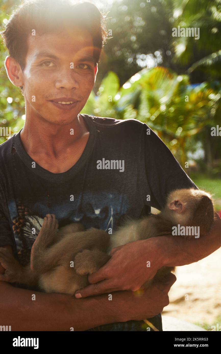 Man with macaque. A monkey keeper in Thailand holding his tame macque. Stock Photo