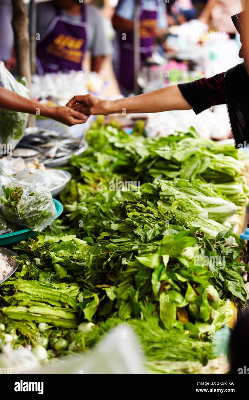 Supporting local traders. Purchasing some vegetables at a Thai herb market. Stock Photo