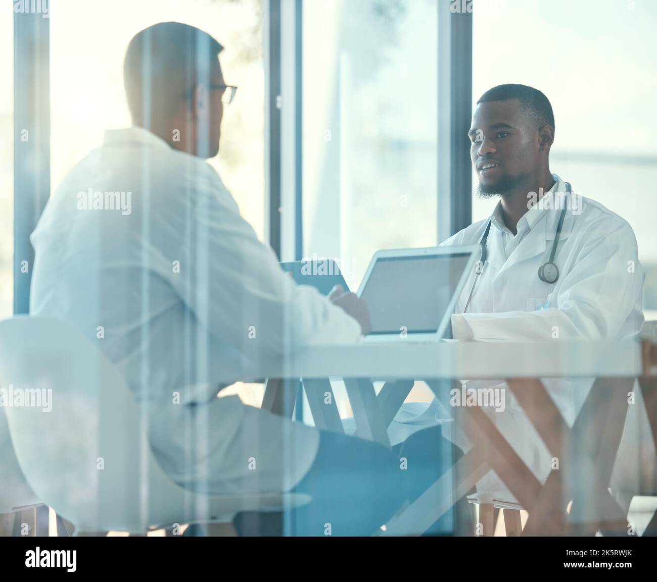 Two doctors talking in a meeting. Colleagues collaborate in a medical meeting in the hospital. Young medical coworkers planning together in a meeting Stock Photo