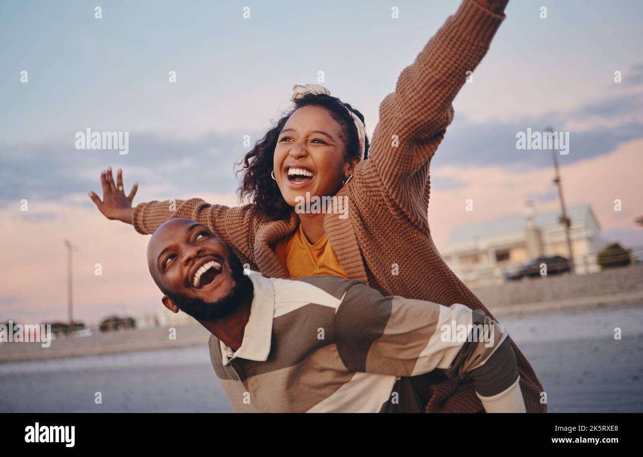 Freedom, love and happy with couple and piggy back ride together on outdoor date for support, sunset or lifestyle vacation. Smile, summer and airplane Stock Photo