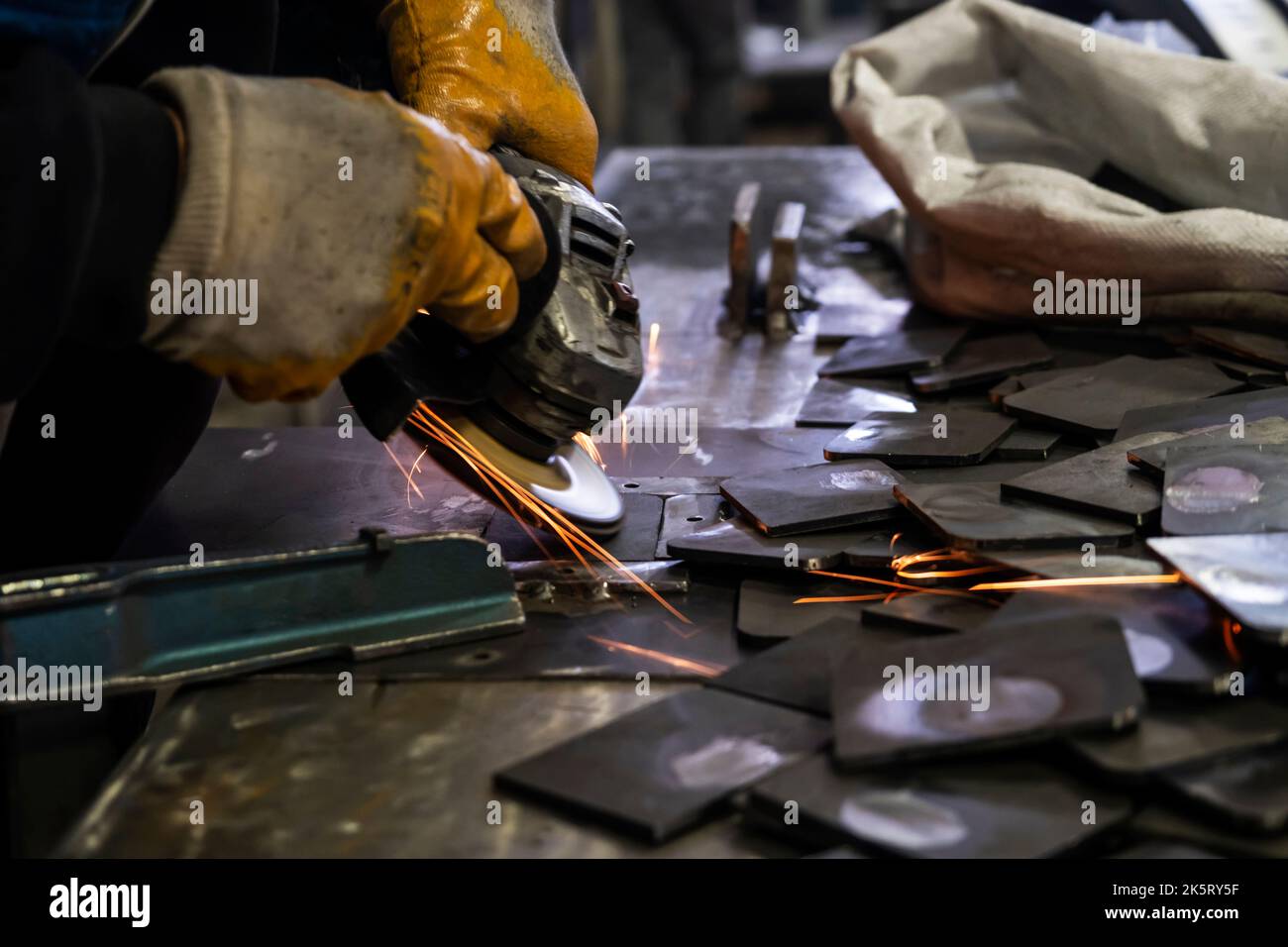 Grinding metal plates with electric wheel in factory. Sparks from the