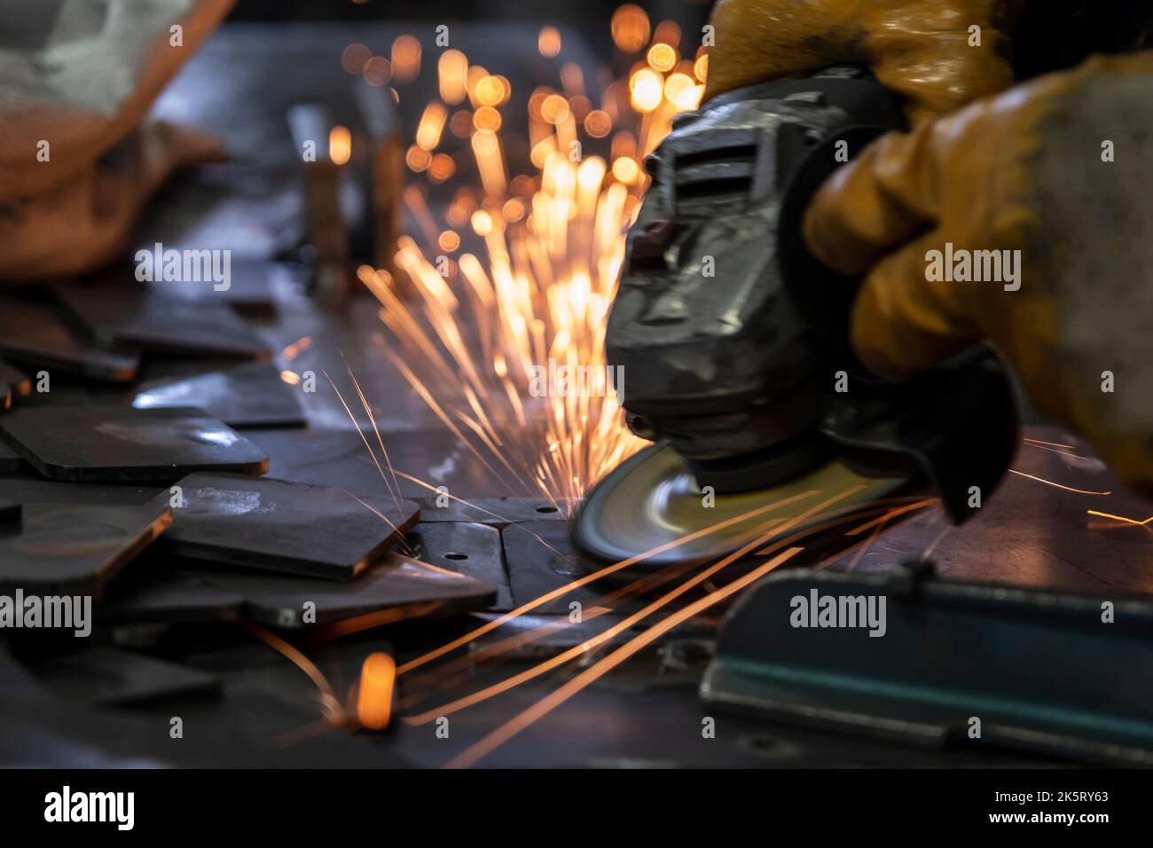 Grinding metal plates with electric wheel in factory. Sparks from the