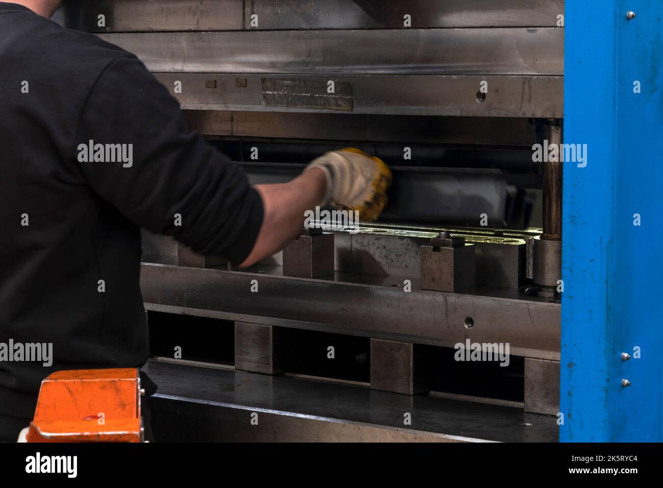 hydraulic press brake or bending machine for flat sheet metal. Worker bending sheet metal on bending machine. Stock Photo