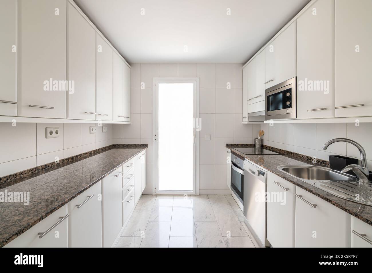 White empty classic kitchen with lots of cabinets with large marble ...