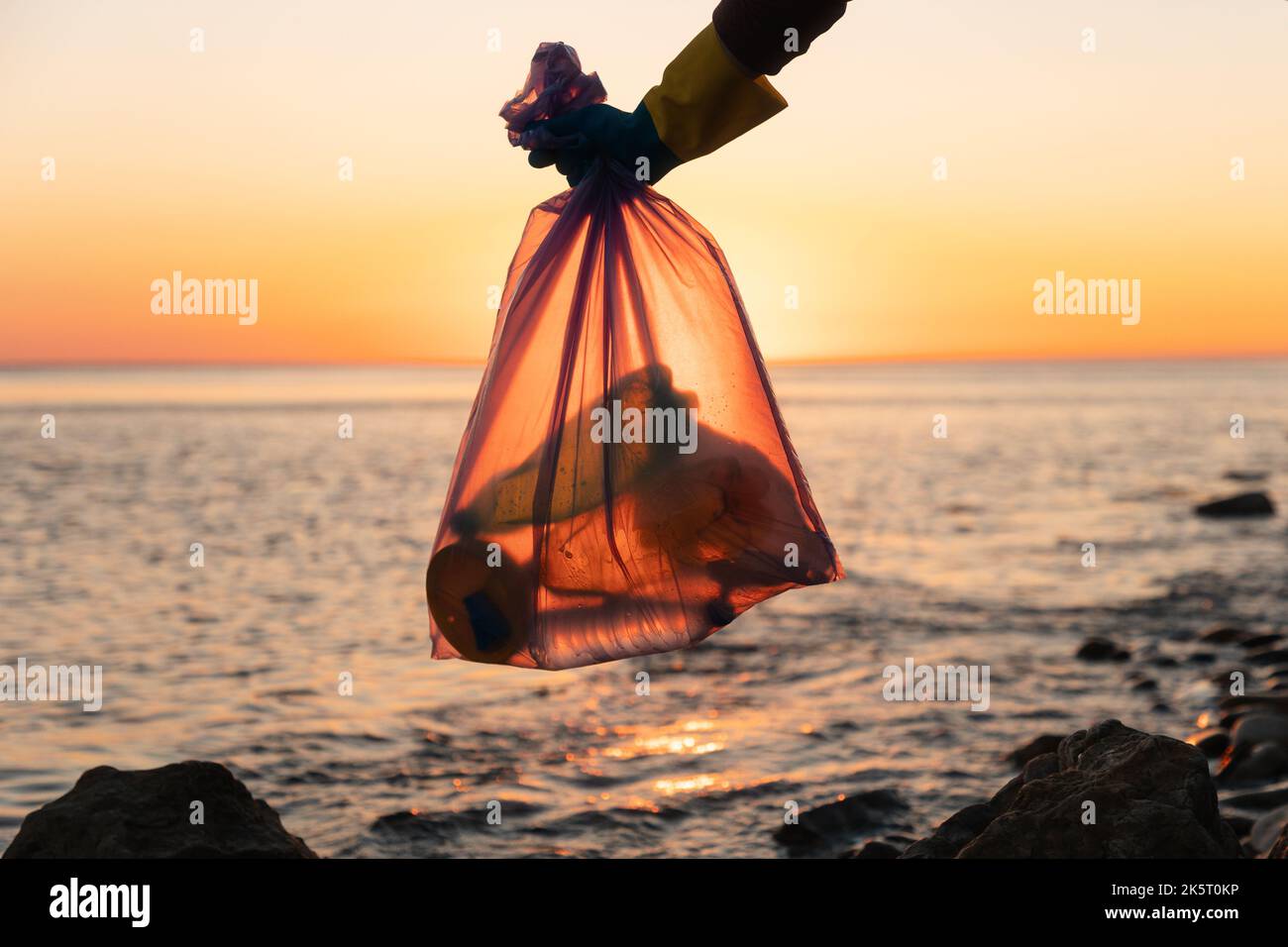 Earth Day. Garbage collection on the shore. A volunteer holds a garbage ...