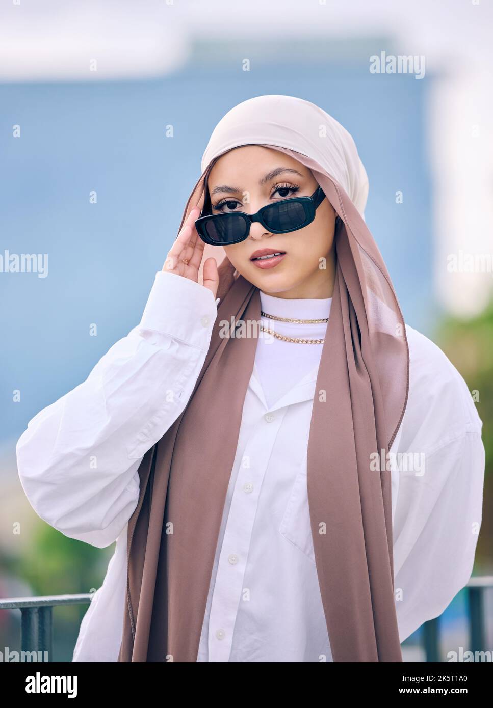 Beautiful young arab woman posing outdoors in a headscarf. Attractive female muslim wearing a hijab posing outside. Shes all about style and fashion Stock Photo