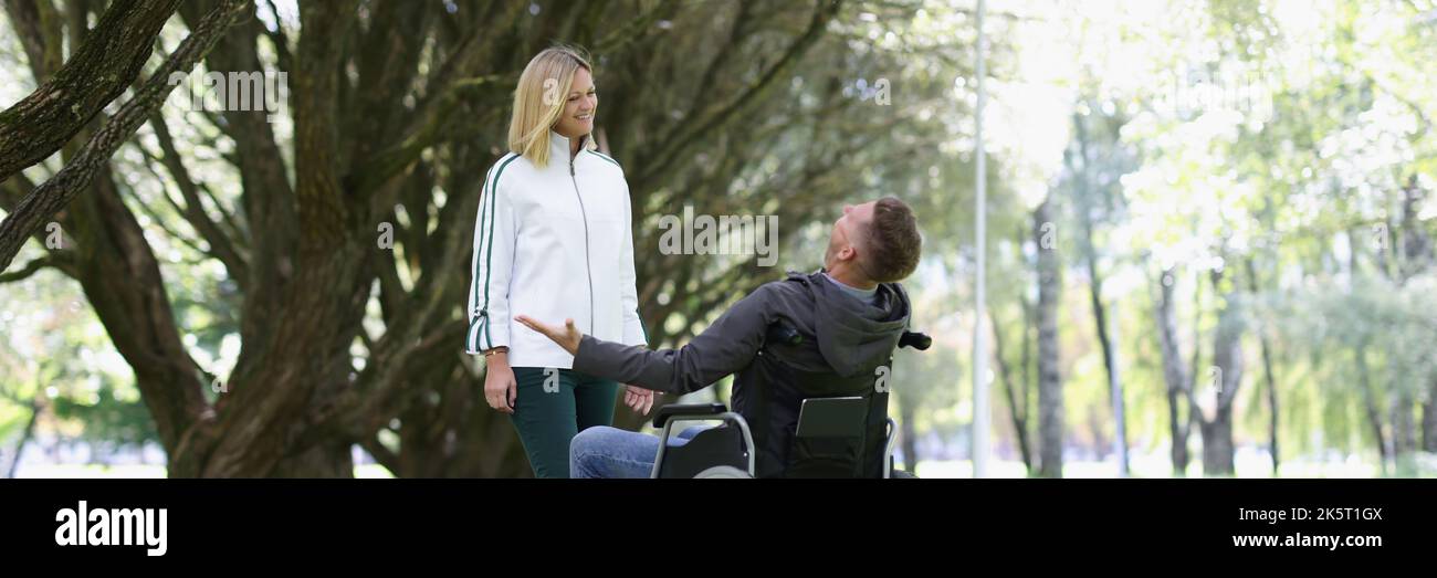Joyful man in a wheelchair meets woman in park Stock Photo - Alamy