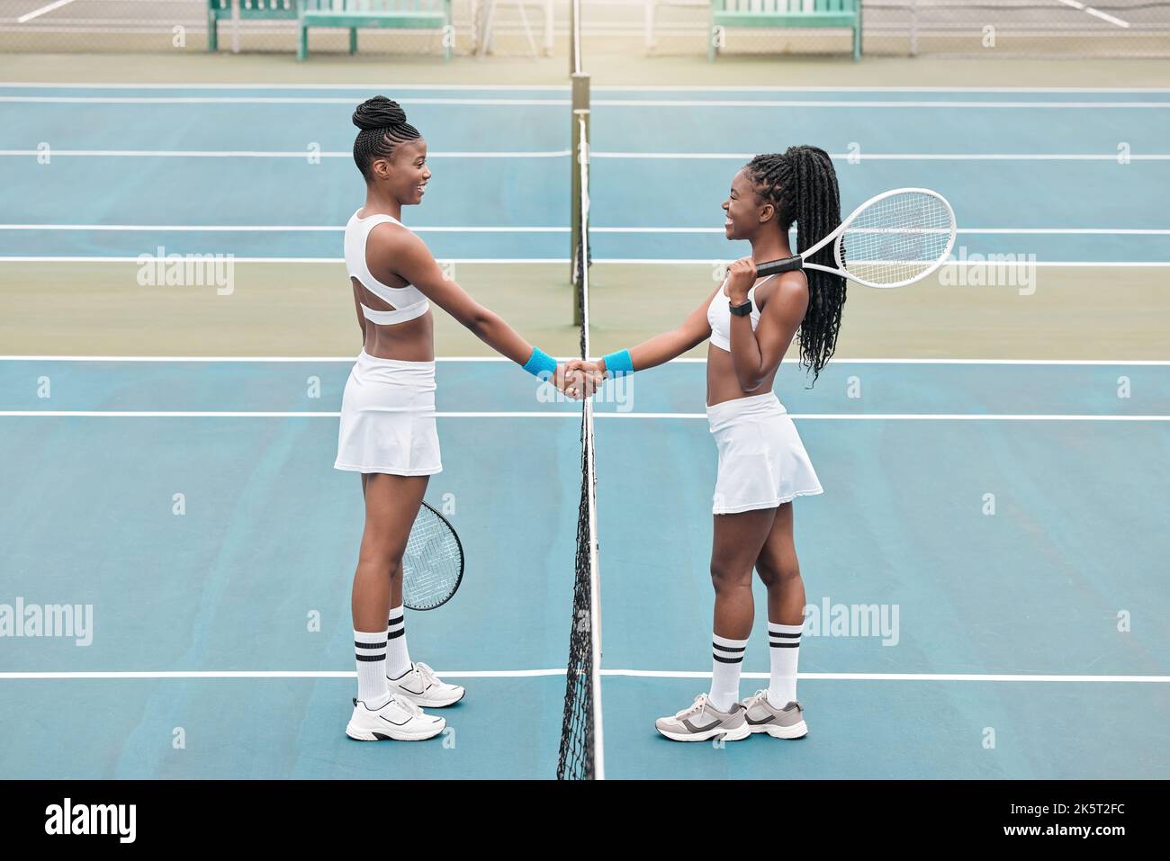 Two women handshake after tennis match. Young friends greet each other before tennis practice. African american athletes bonding after a tennis match Stock Photo