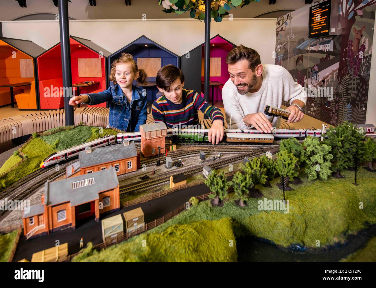 EDITORIAL USE ONLY Broadcaster and railway historian Tim Dunn adds the finishing touches to a Hornby model train set featuring Flying Scotsman and an LNER Azuma train, with Holly, aged 5, and Miles Trainor-McFerran, aged 10, at the new London North Eastern Railway (LNER) Family Lounge at King's Cross Station, ahead of it opening to the public on Wednesday October 12. Issue date: Monday October 10, 2022. Stock Photo