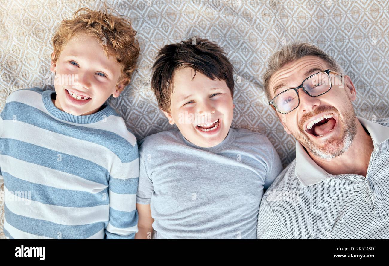 Carefree loving father from above relaxing with his cute little playful sons. Happy caucasian family bonding together. Cheerful kids spending quality Stock Photo