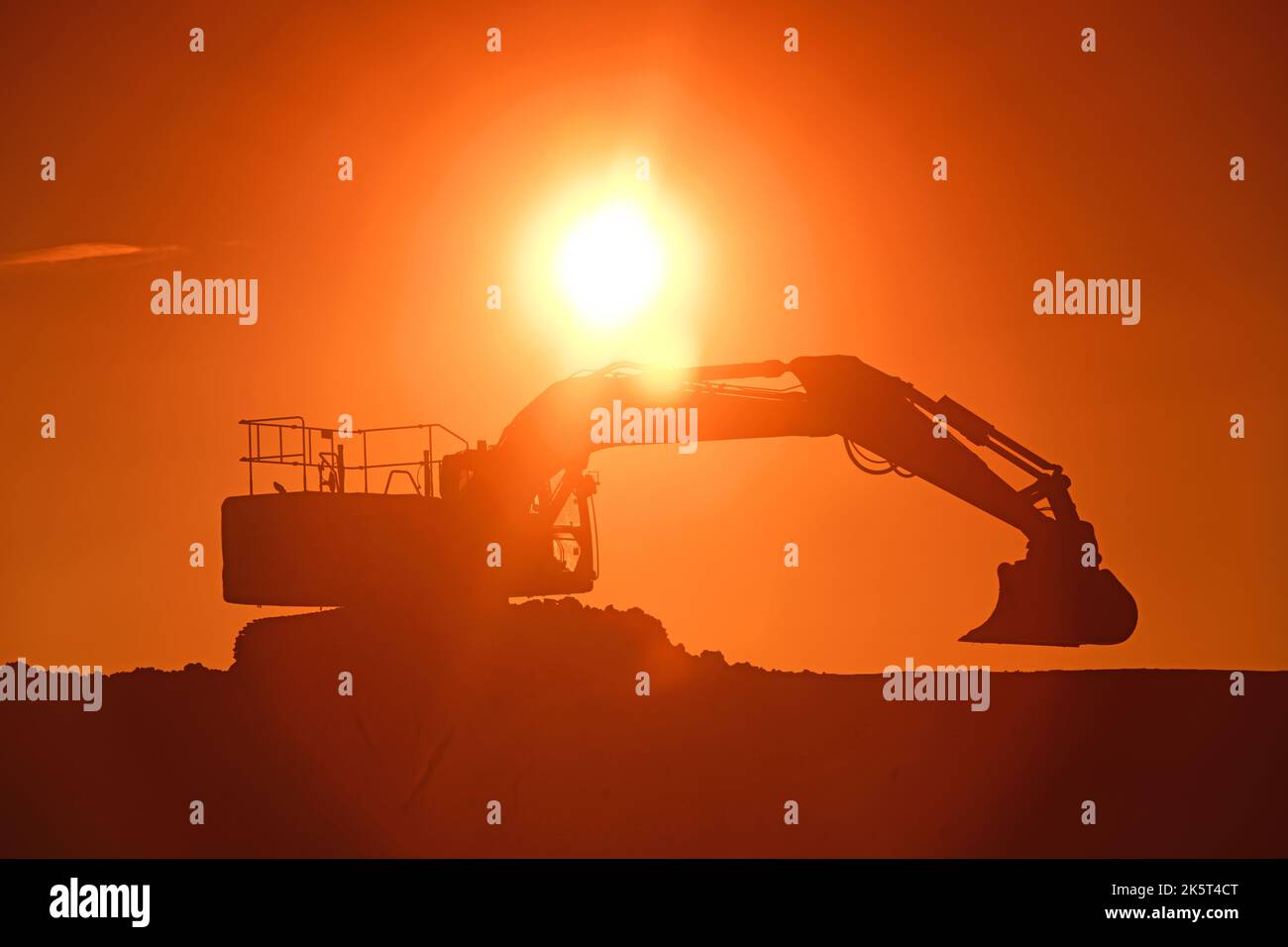 caterpillar digger working on site at sunset united kingdom Stock Photo
