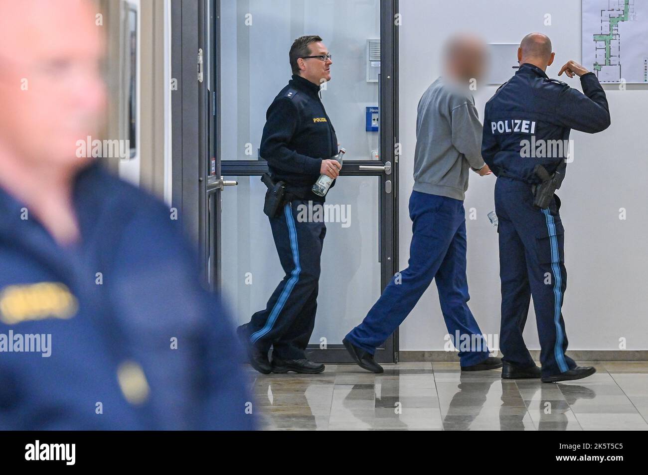 Deggendorf, Germany. 10th Oct, 2022. The defendant (2nd from right) is led by police officers into the hearing room of the district court. Credit: Armin Weigel/dpa - Nutzung nur nach schriftlicher Vereinbarung mit der dpa/Alamy Live News Stock Photo