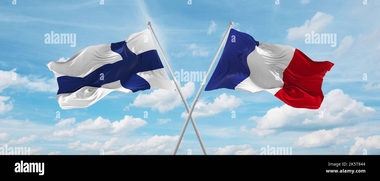 two crossed flags France and finland waving in wind at cloudy sky ...