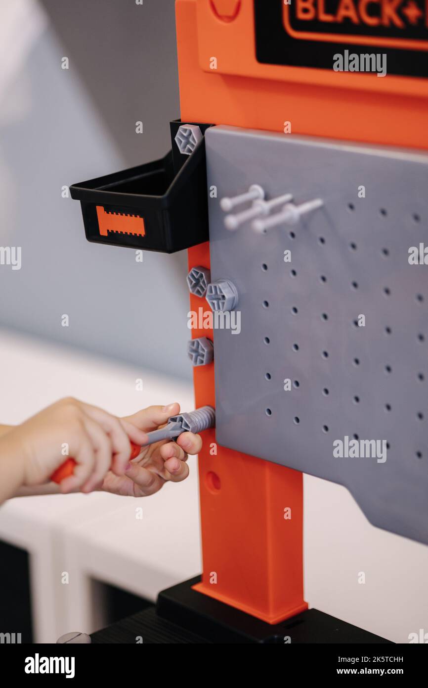 Little boy is playing with children's tools and screwing a toy bolt with a screwdriver Stock Photo