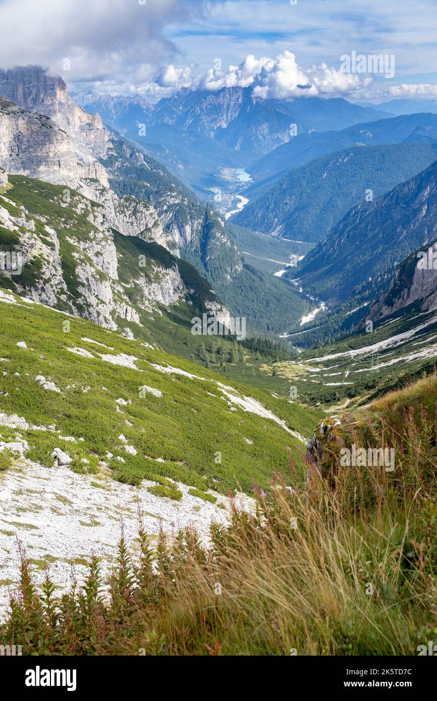 A vertical shot of mountain ranges with blue cloudy sky in a valley ...